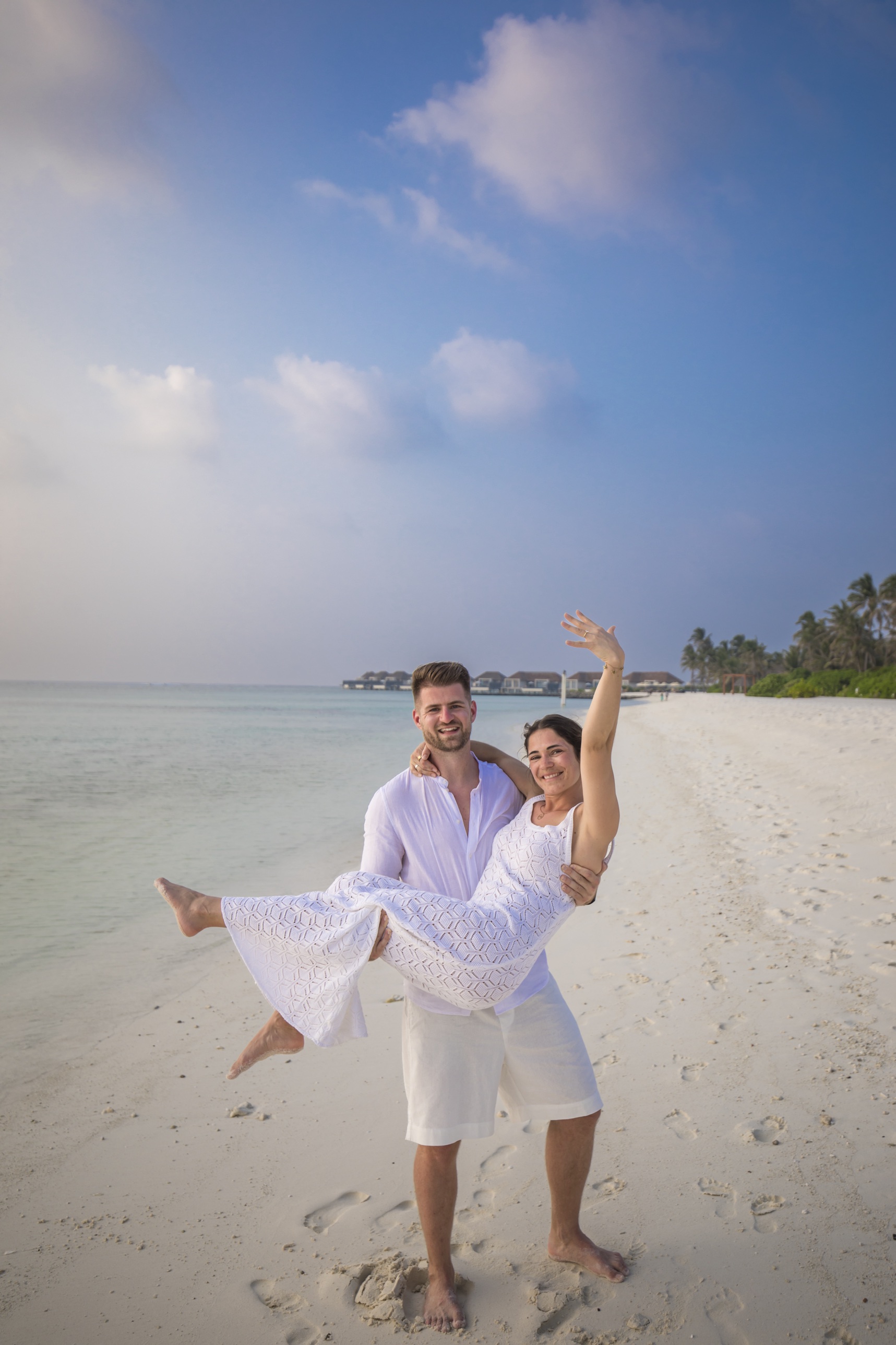 Nick trägt Romina am Strand auf den Armen